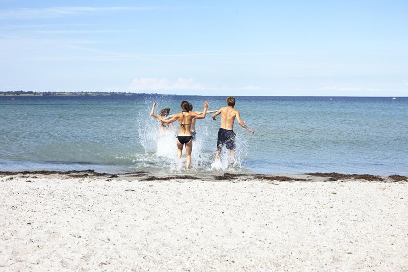 Badende laufen ins Wasser am Sandstrand bei Gedser